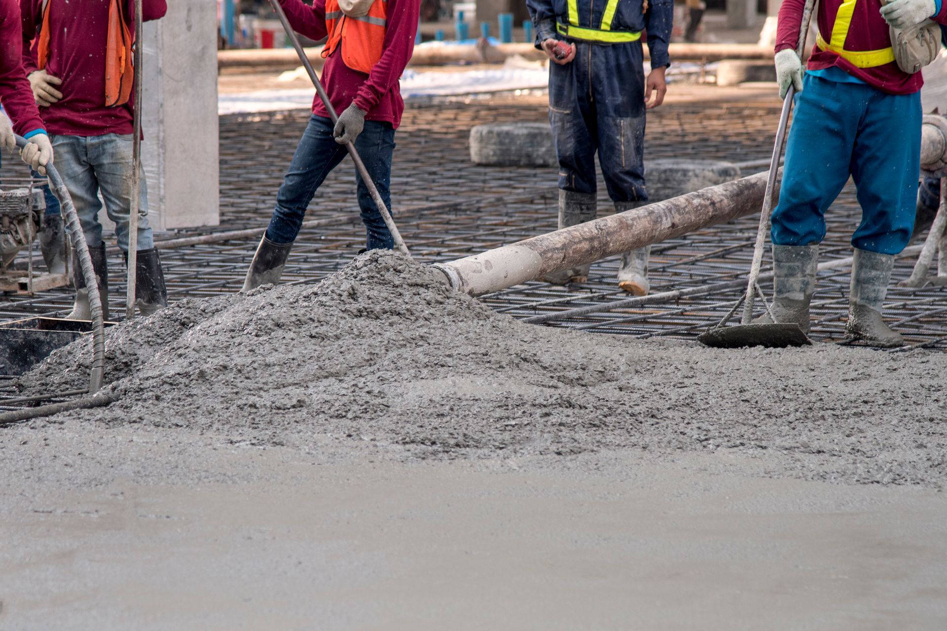 Construction workers pouring and leveling concrete on a construction site.
