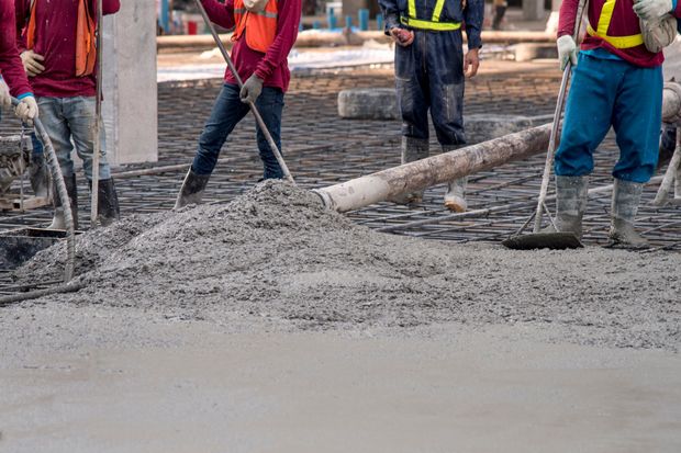 Construction workers pouring and leveling concrete on a construction site.