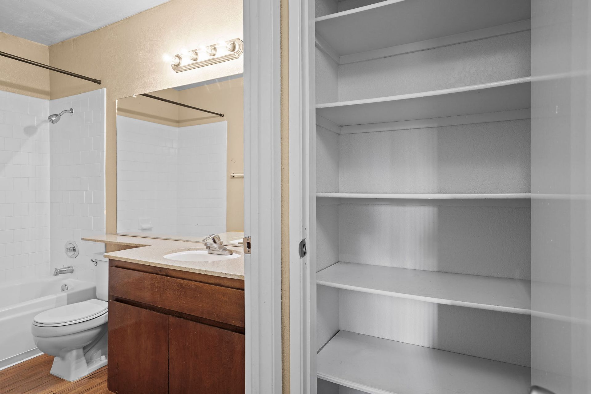 Bathroom with toilet, vanity, mirror, and open white closet shelves