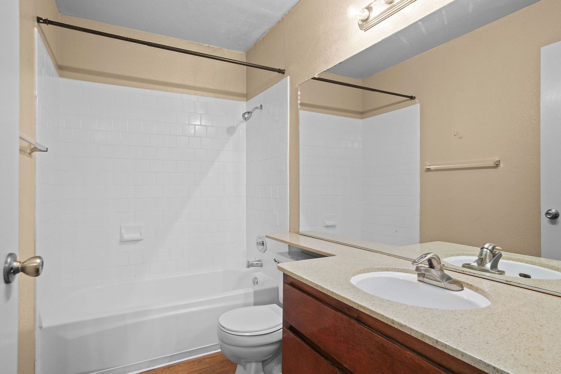 Bathroom with tub-shower combo, toilet, mirror, and sink vanity in neutral tones