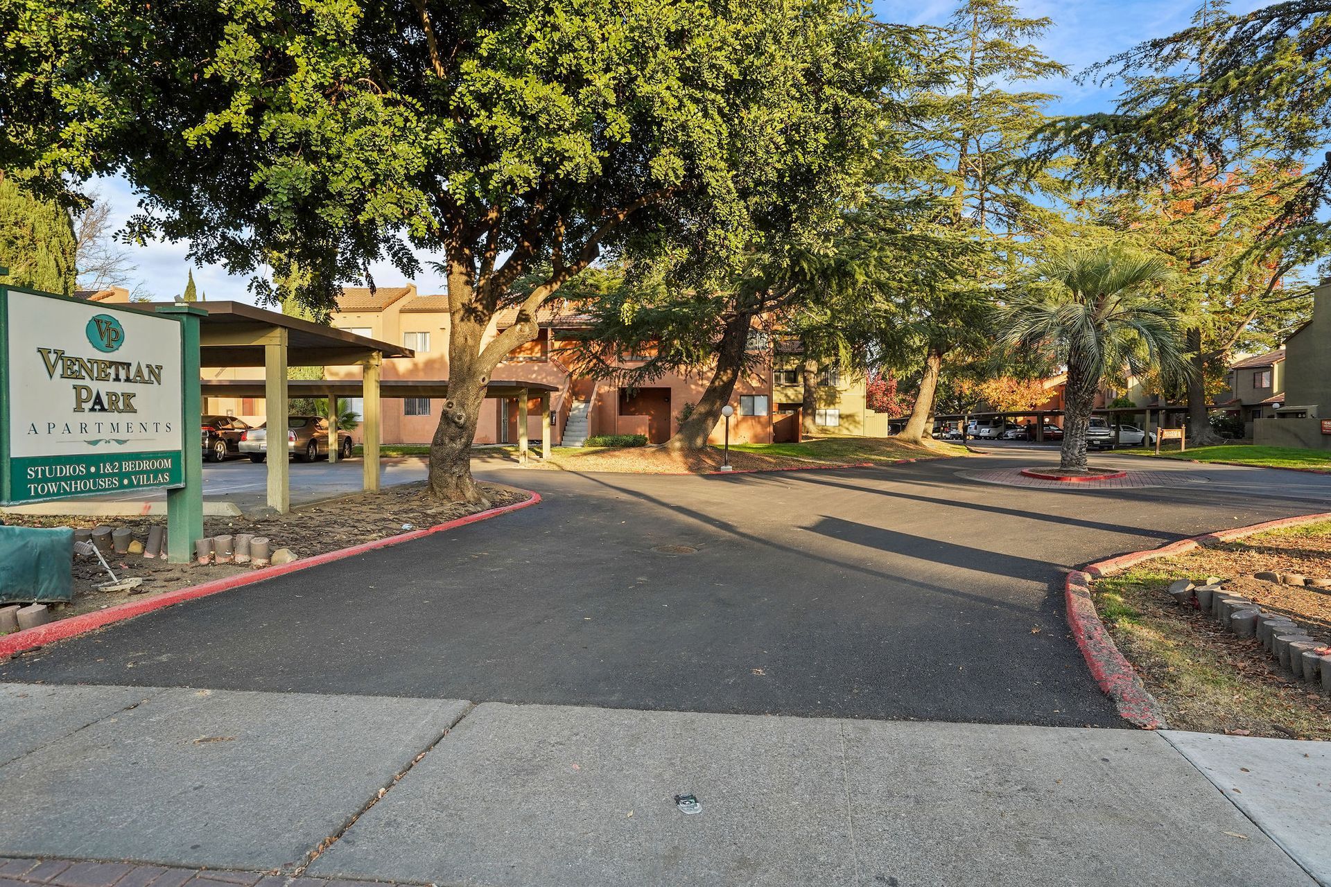 Vineland Park entrance with sign, tree-lined driveway, and brick buildings in the background