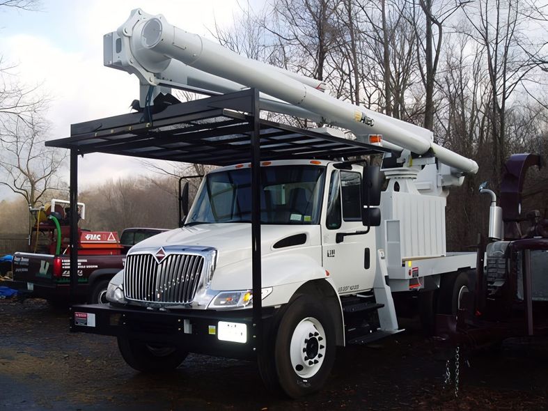White utility truck with a large extendable boom. Outdoor setting.
