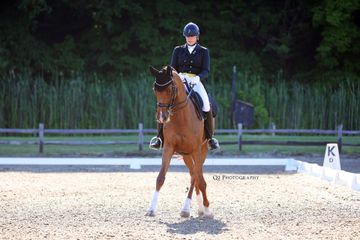 A woman is riding a brown horse in a dirt arena