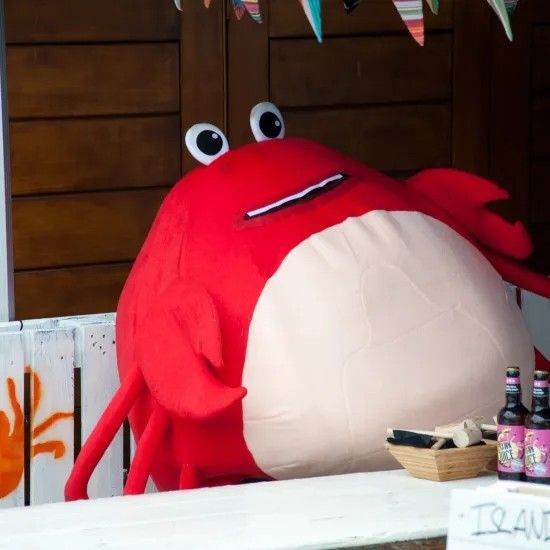 Red crab mascot behind a white counter, seemingly at a food stall.