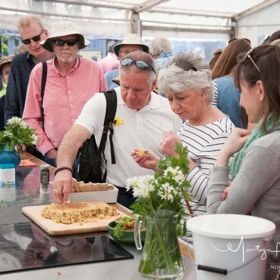 People sampling food at an outdoor event, some looking at food, some eating.