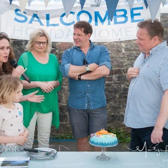 People at a table with cake and banner reading 