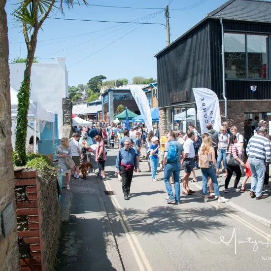 Street market with many people, shops, white tents, sunny day.
