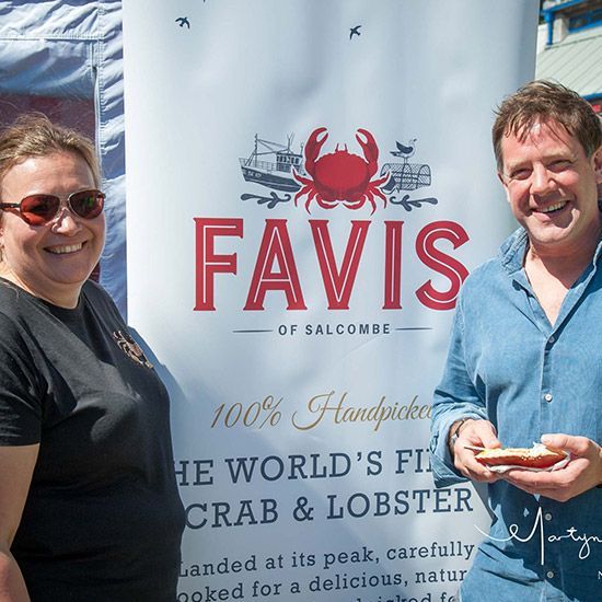 Two people smiling by a banner that says 