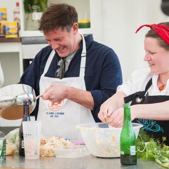 Two people cooking in a kitchen, one pouring liquid from a pot, the other mixing ingredients in a bowl.