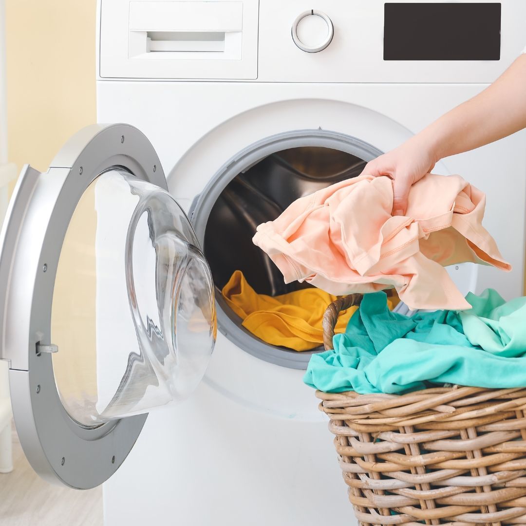 A person is putting clothes in a washing machine.