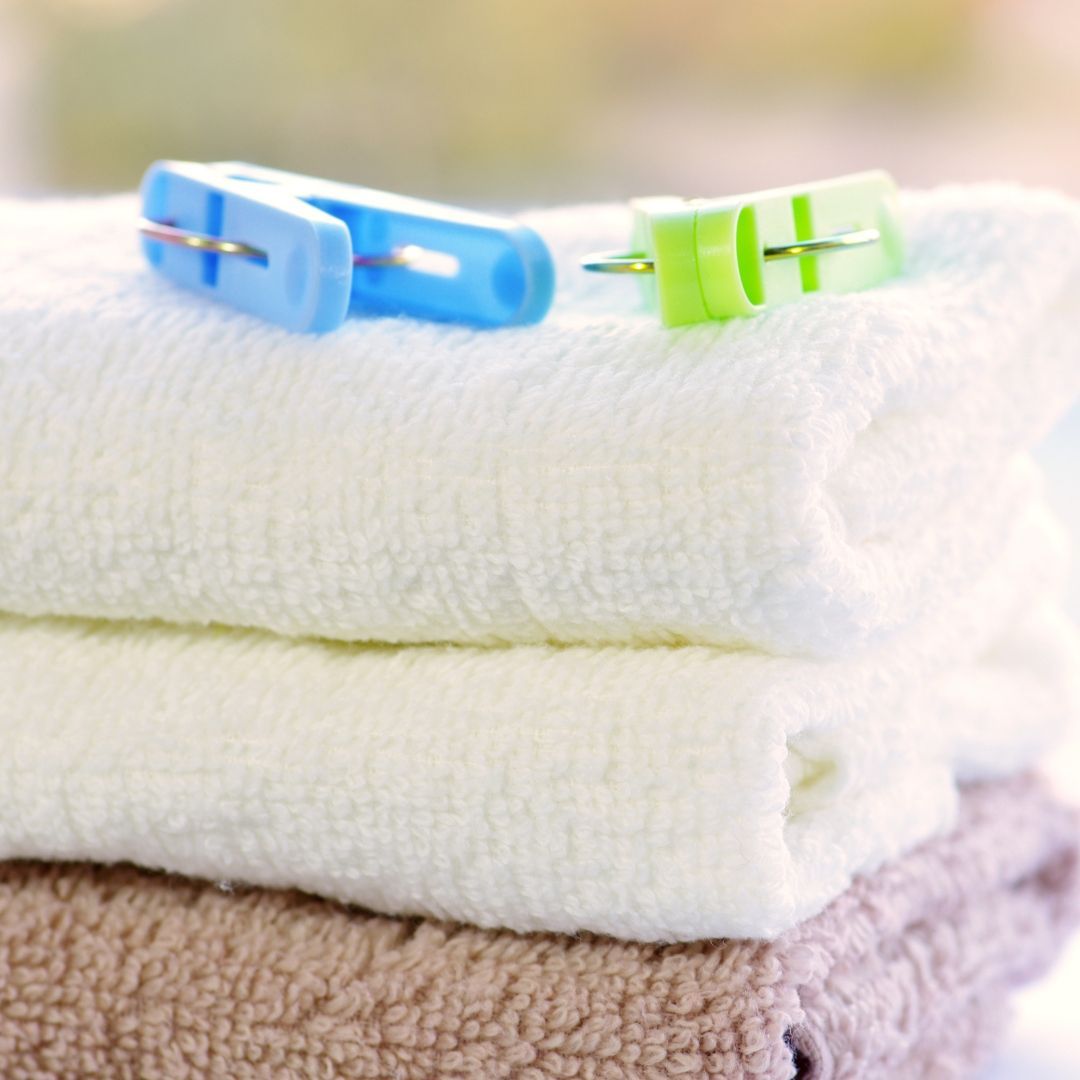 A stack of towels with blue and green clothespins on top