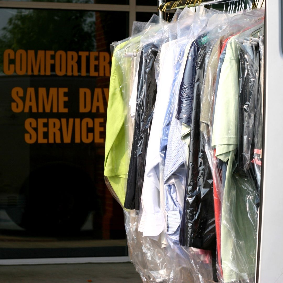 Clothes hanging in front of a window that says comforter same day service