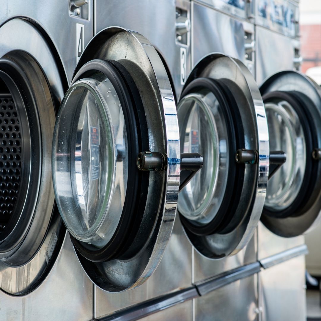 A row of washing machines are lined up in a laundromat.