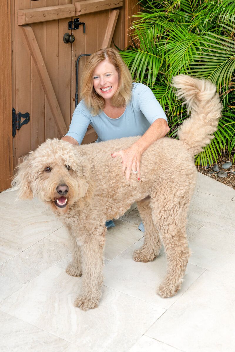 A woman is standing next to a large brown dog.