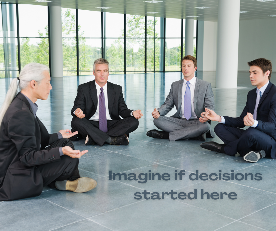 four professional men in suits meditating while sitting on the floor.