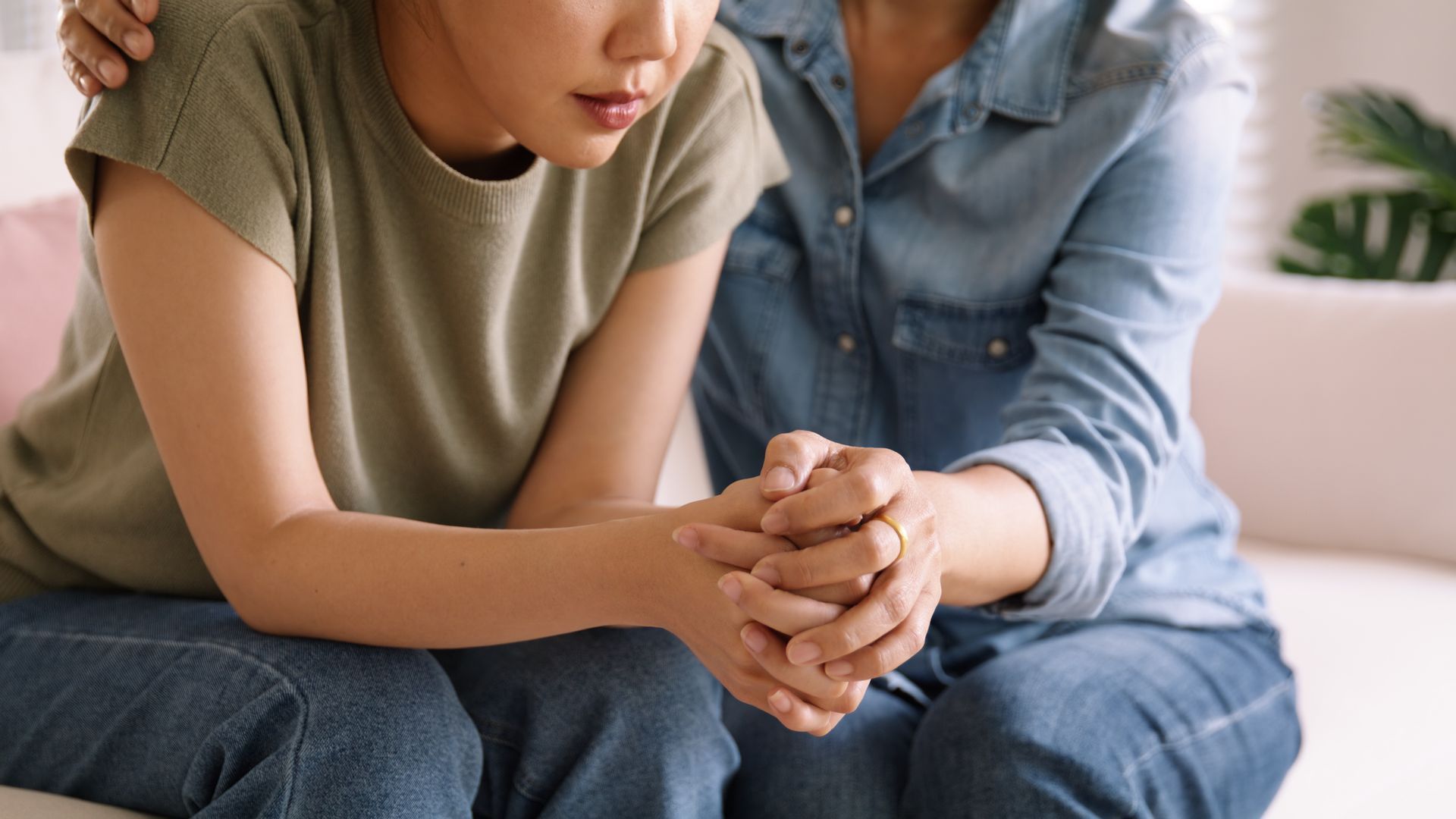 A woman is holding a child 's hand while sitting on a couch.
