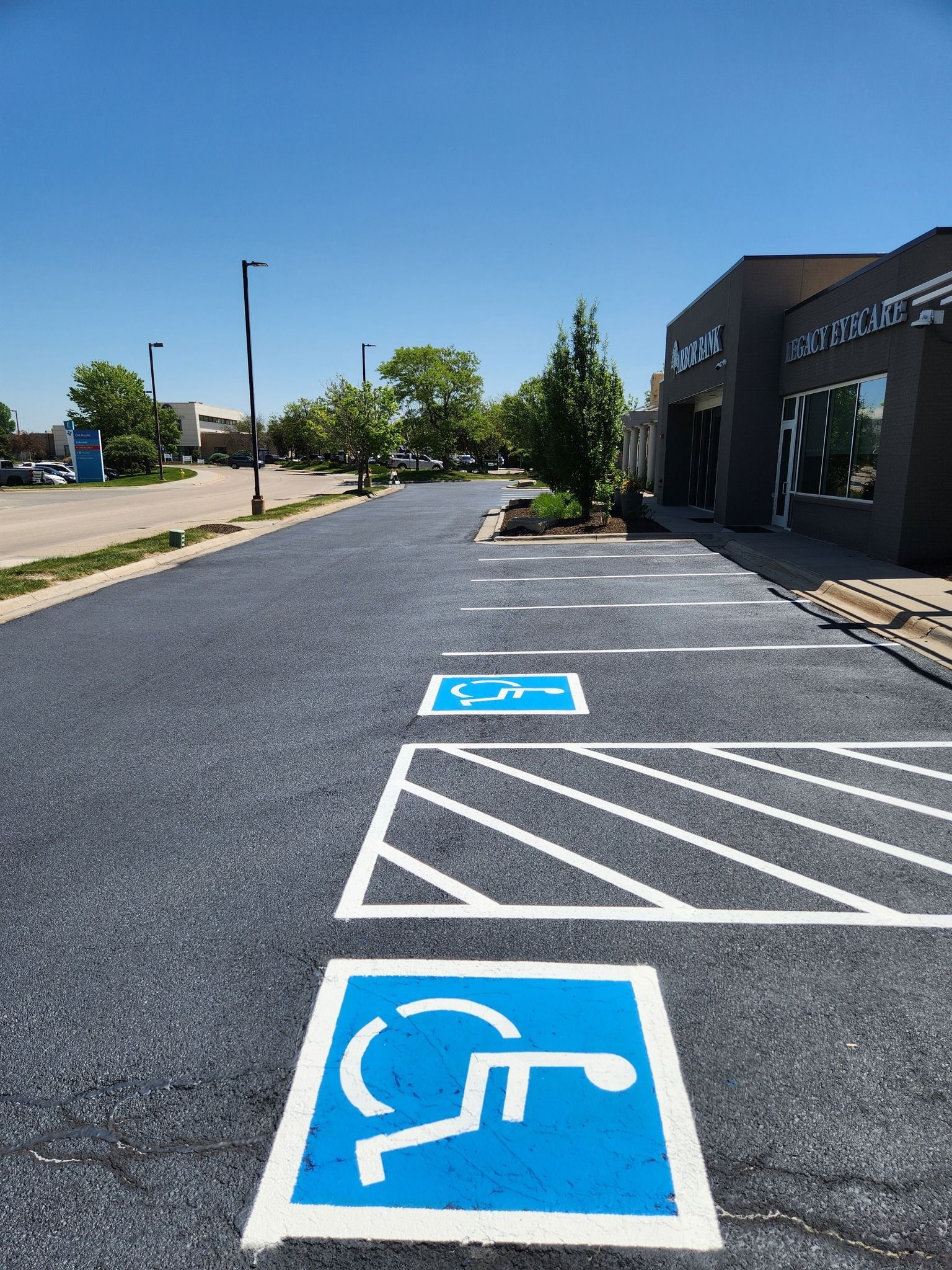 Two blue and white handicap parking symbols painted on freshly paved asphalt next to a building.