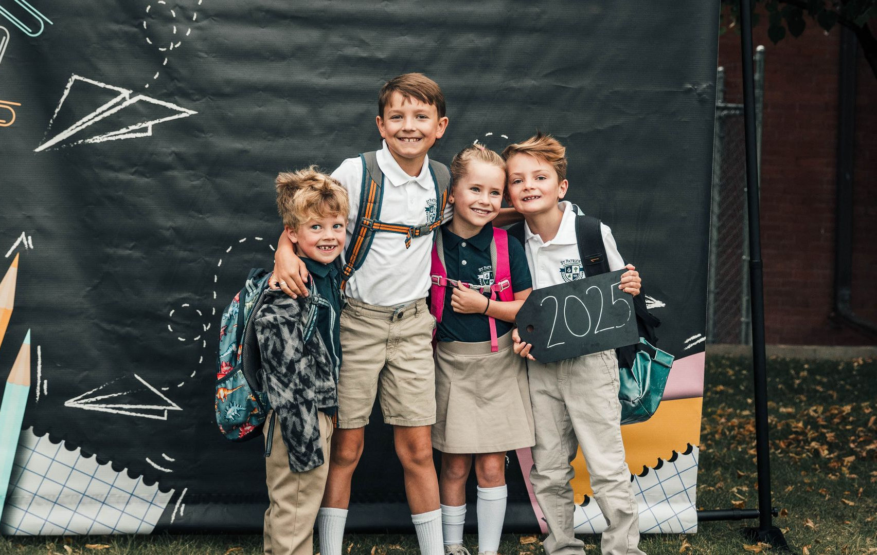 Three children are sitting on the grass eating lunch.