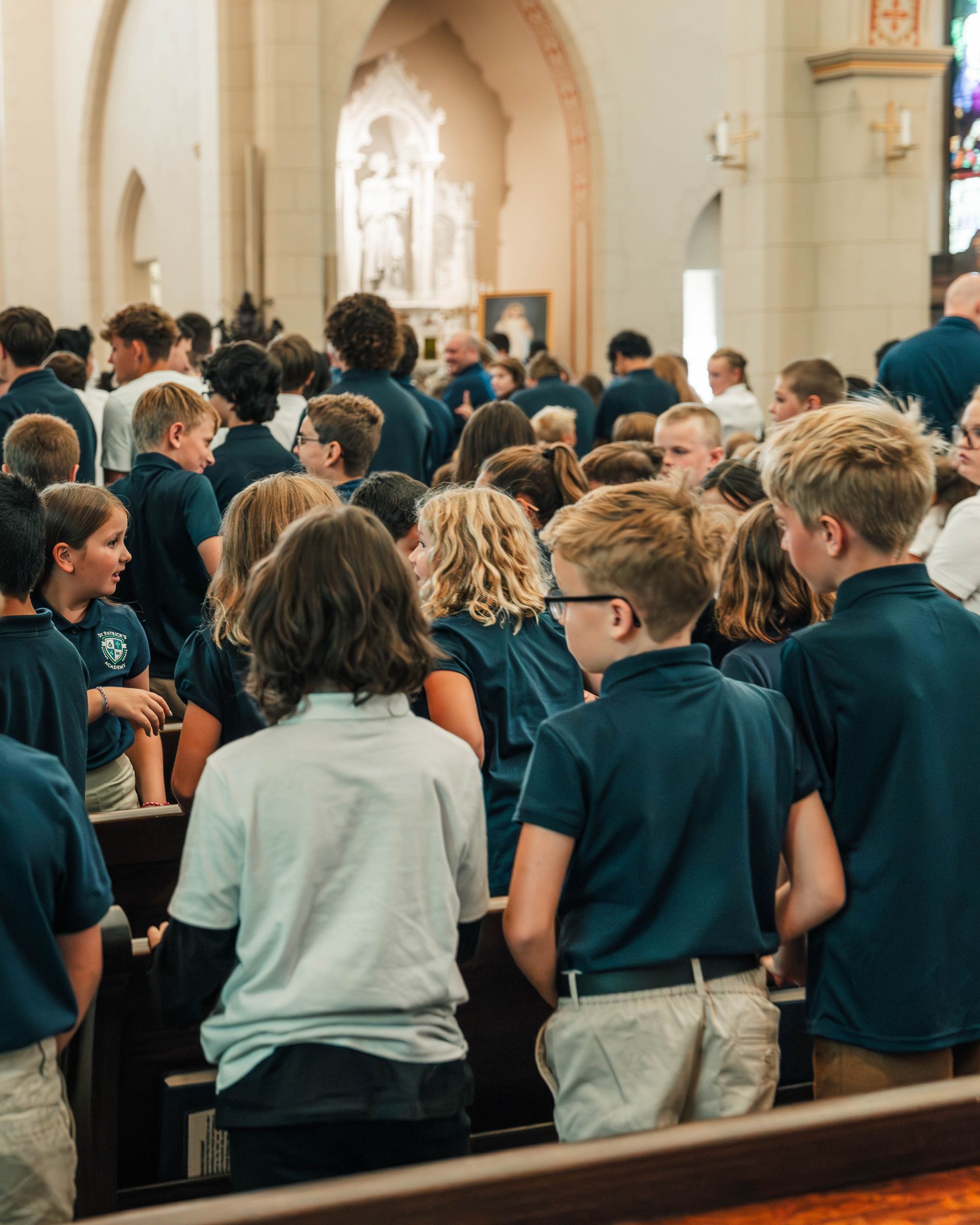 Kids walking down a hallway; one child making horns gesture.