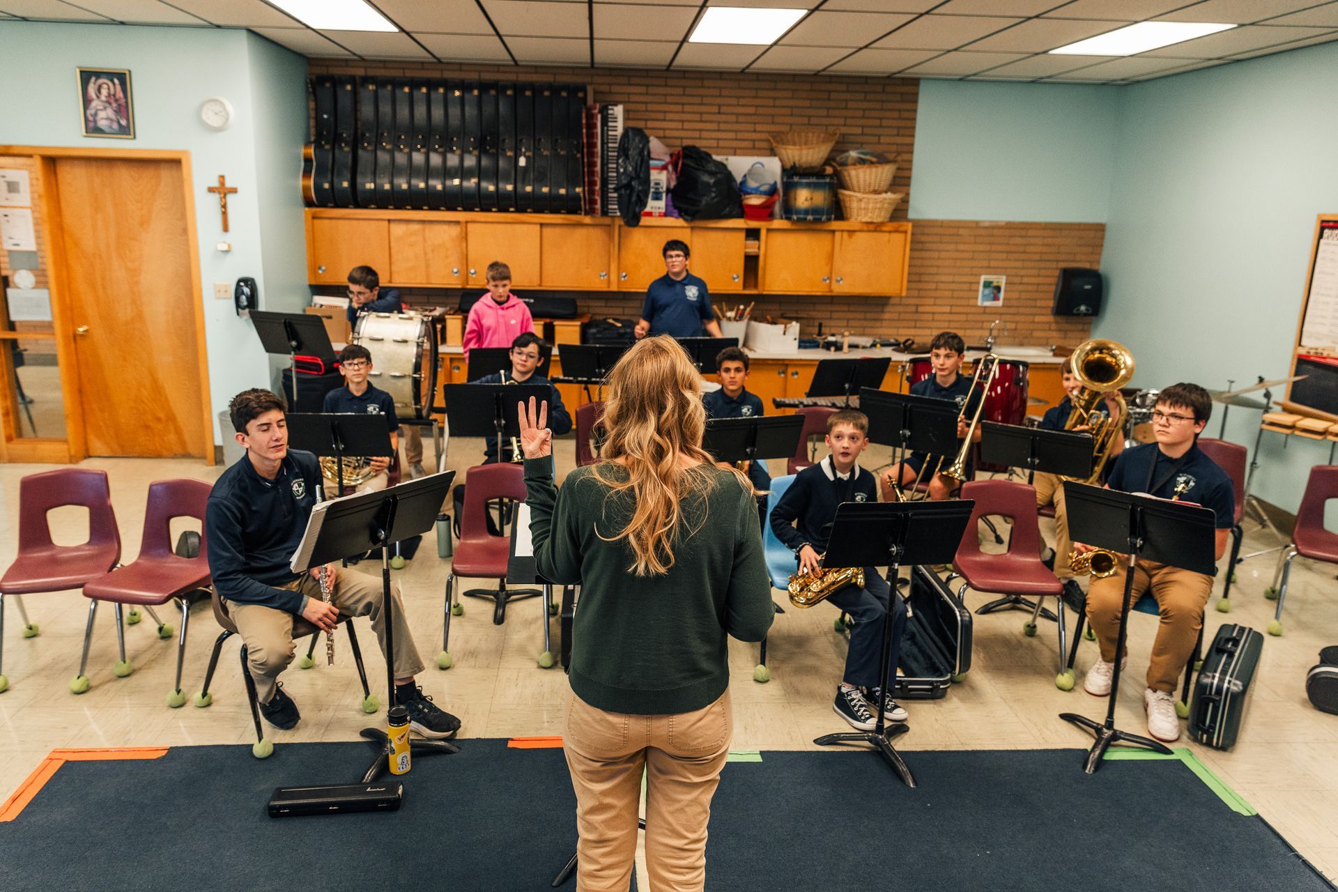 Man holding a blank brown sign overhead, standing in a room with a second man looking on.