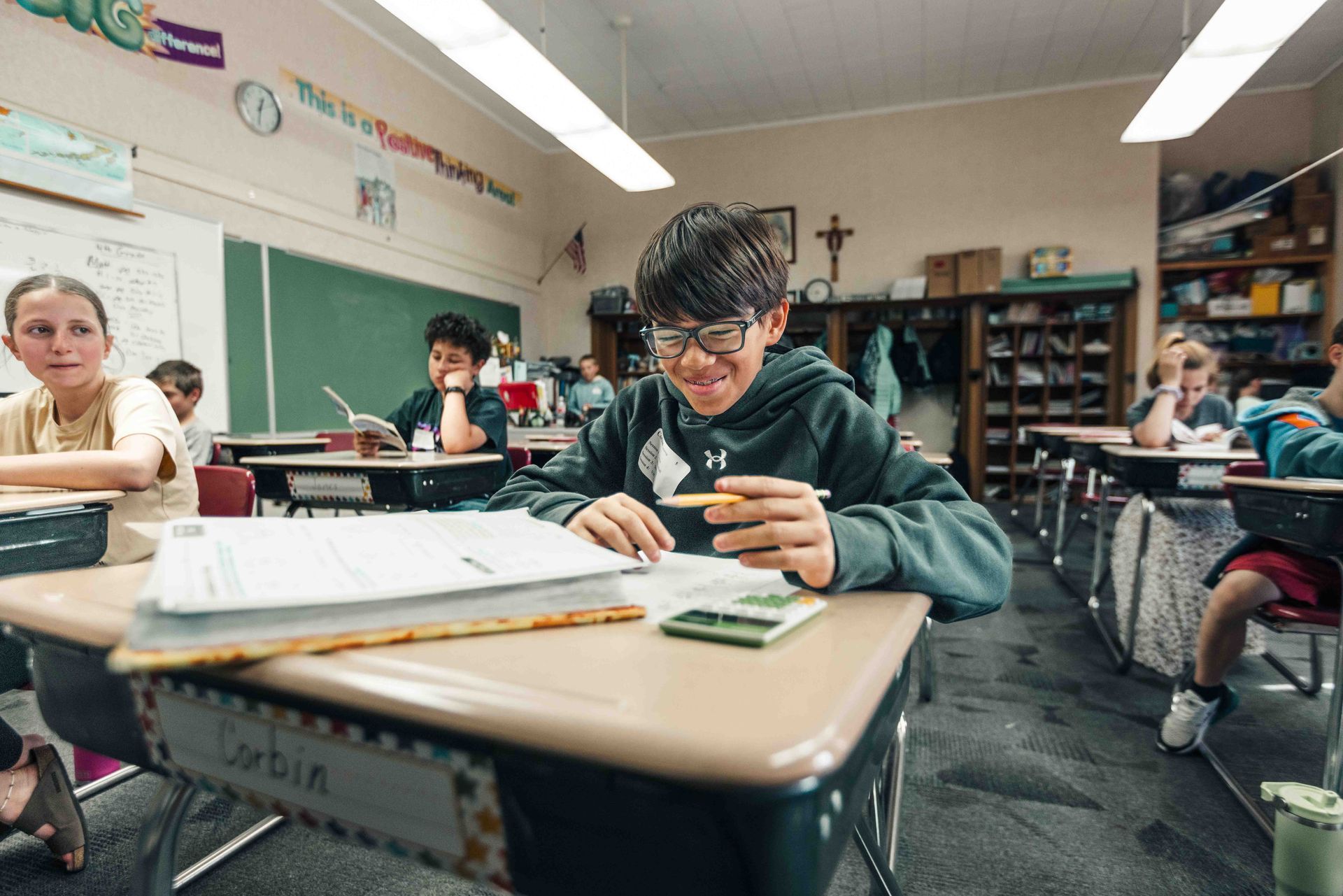 A boy is sitting at a desk in a classroom.