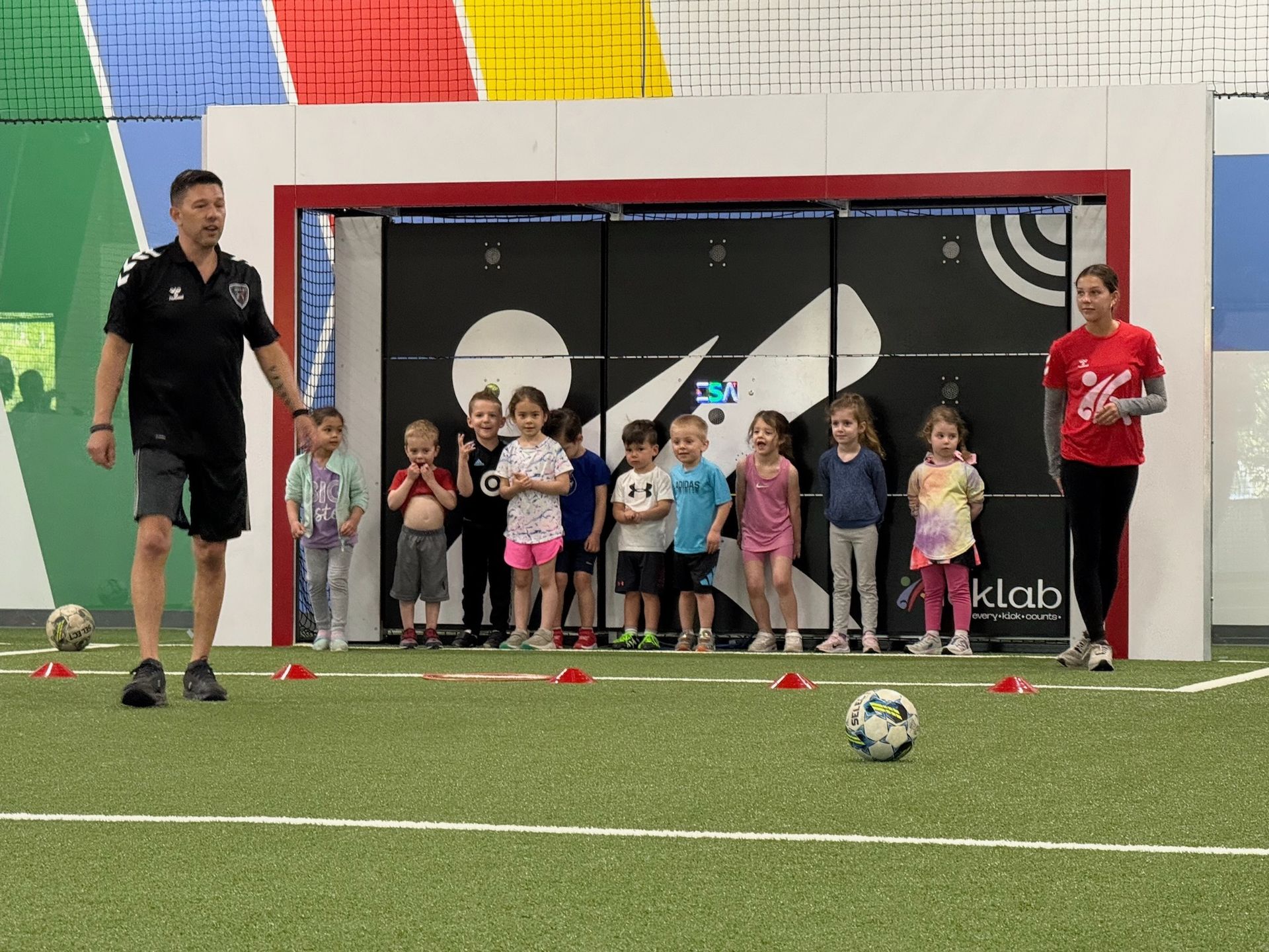 A group of children are standing around a soccer ball on a field.