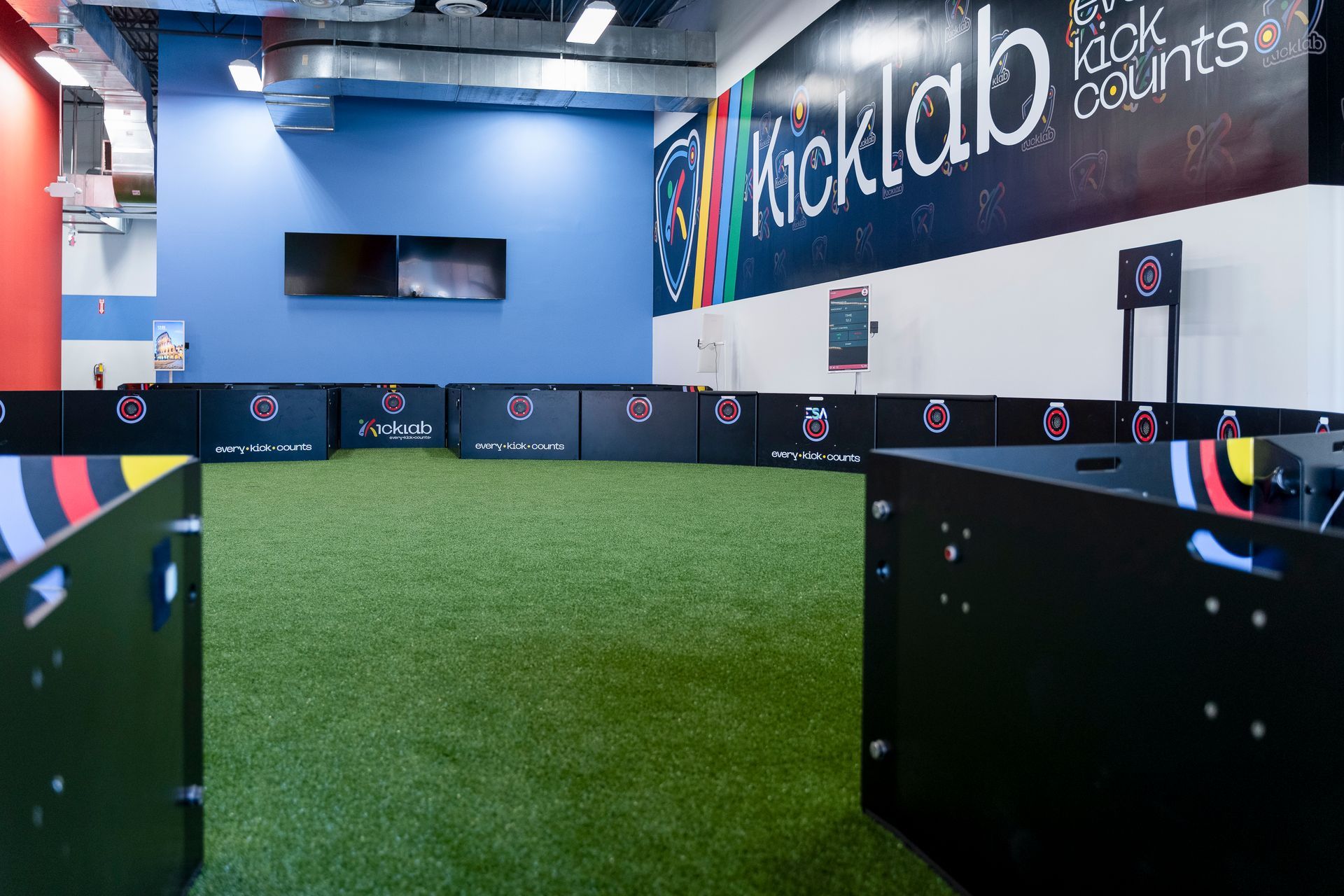 A room with a green field and a sign that says kicklab on the wall.