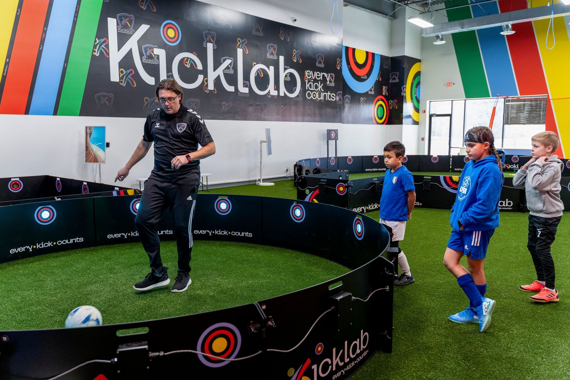 A group of children are playing soccer in a gym.