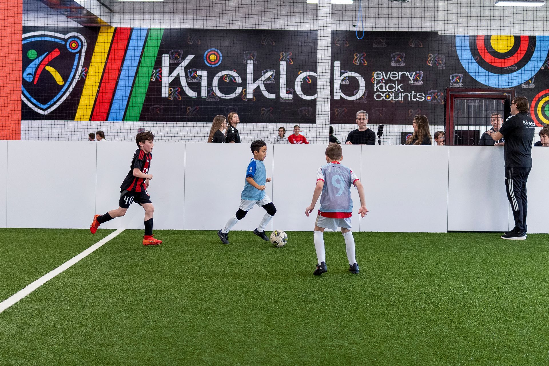 A group of young boys are playing soccer on a indoor field.