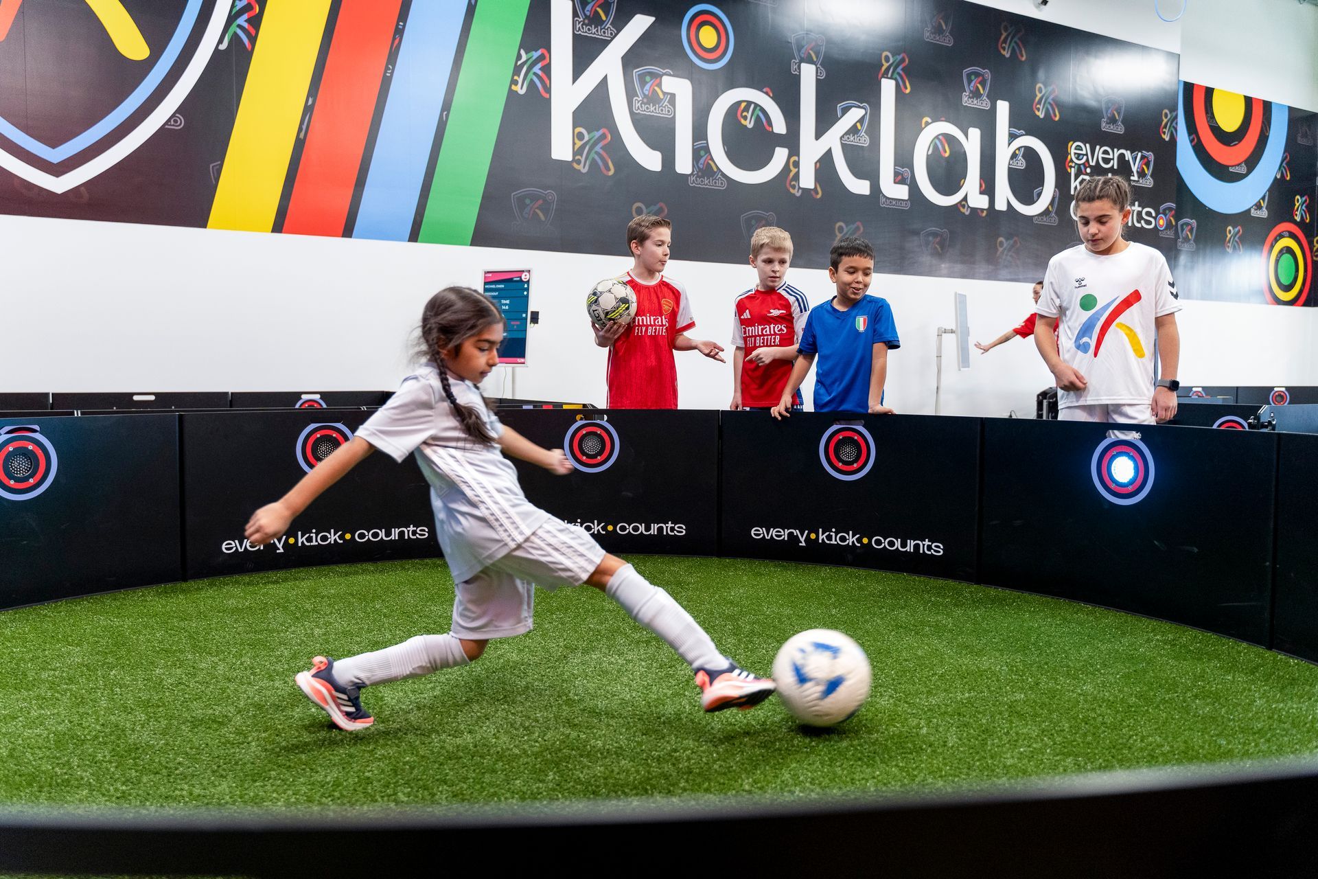 A group of children are playing soccer on a soccer field.