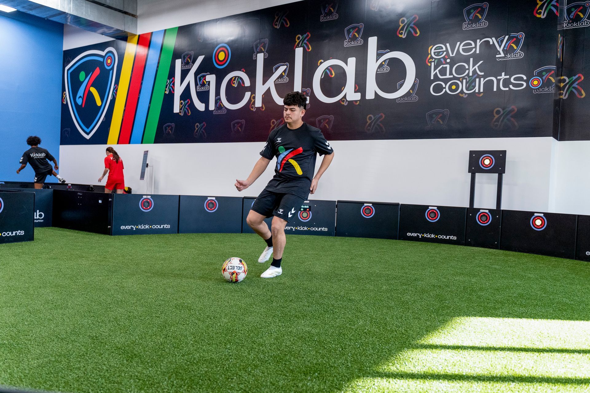 A man is kicking a soccer ball in a gym.
