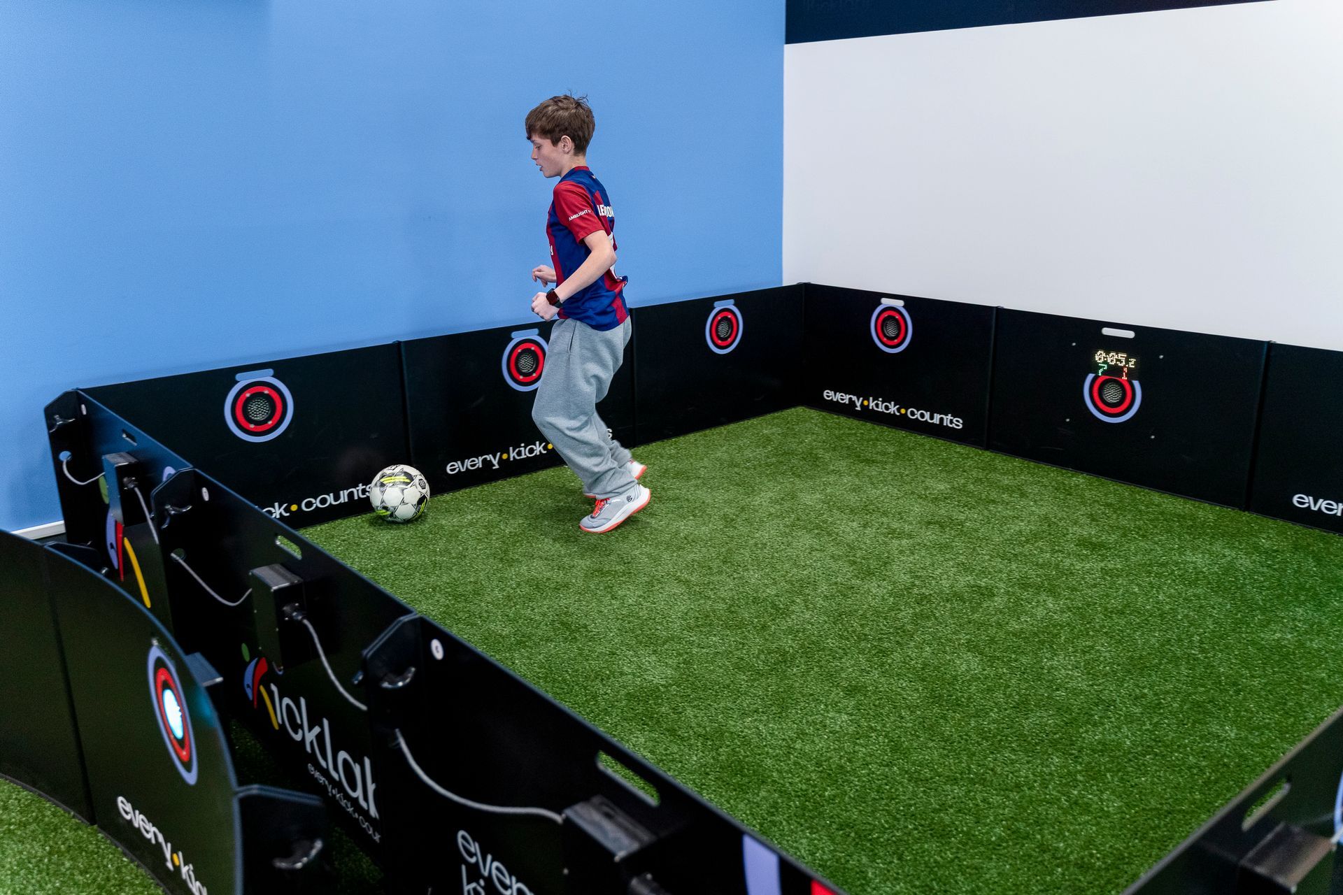 A young boy is kicking a soccer ball in a room.