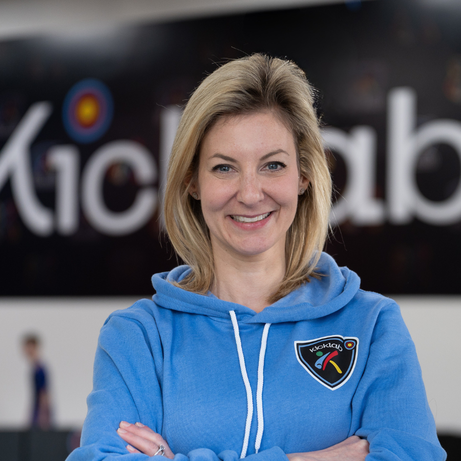 Woman in a blue hoodie smiles in front of a 