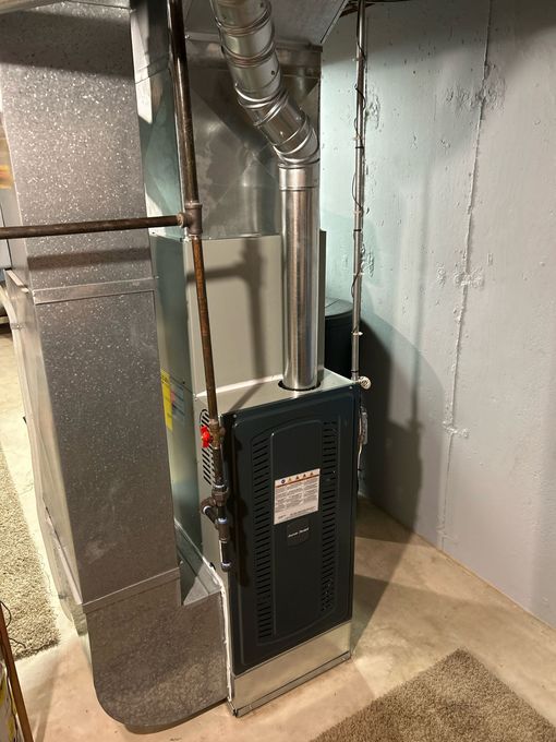Furnace in a basement setting with ductwork and vent pipe. Metallic silver and gray color scheme.