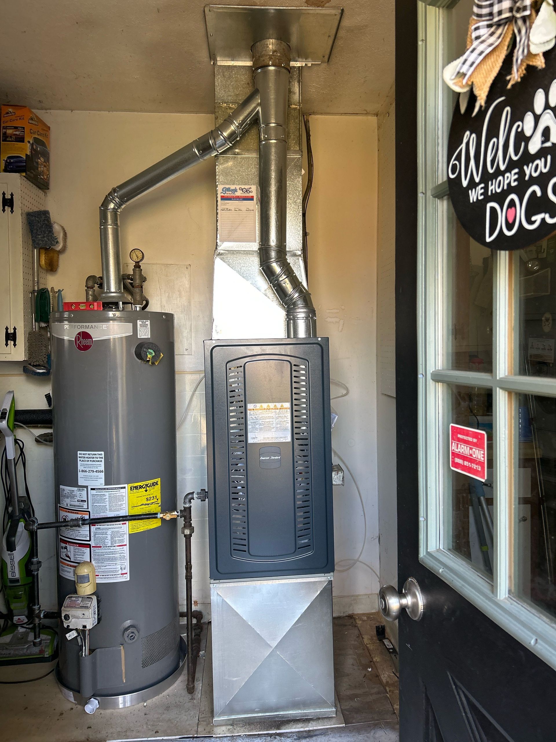 Water heater and furnace in a garage. Metal ducts and pipes are visible.