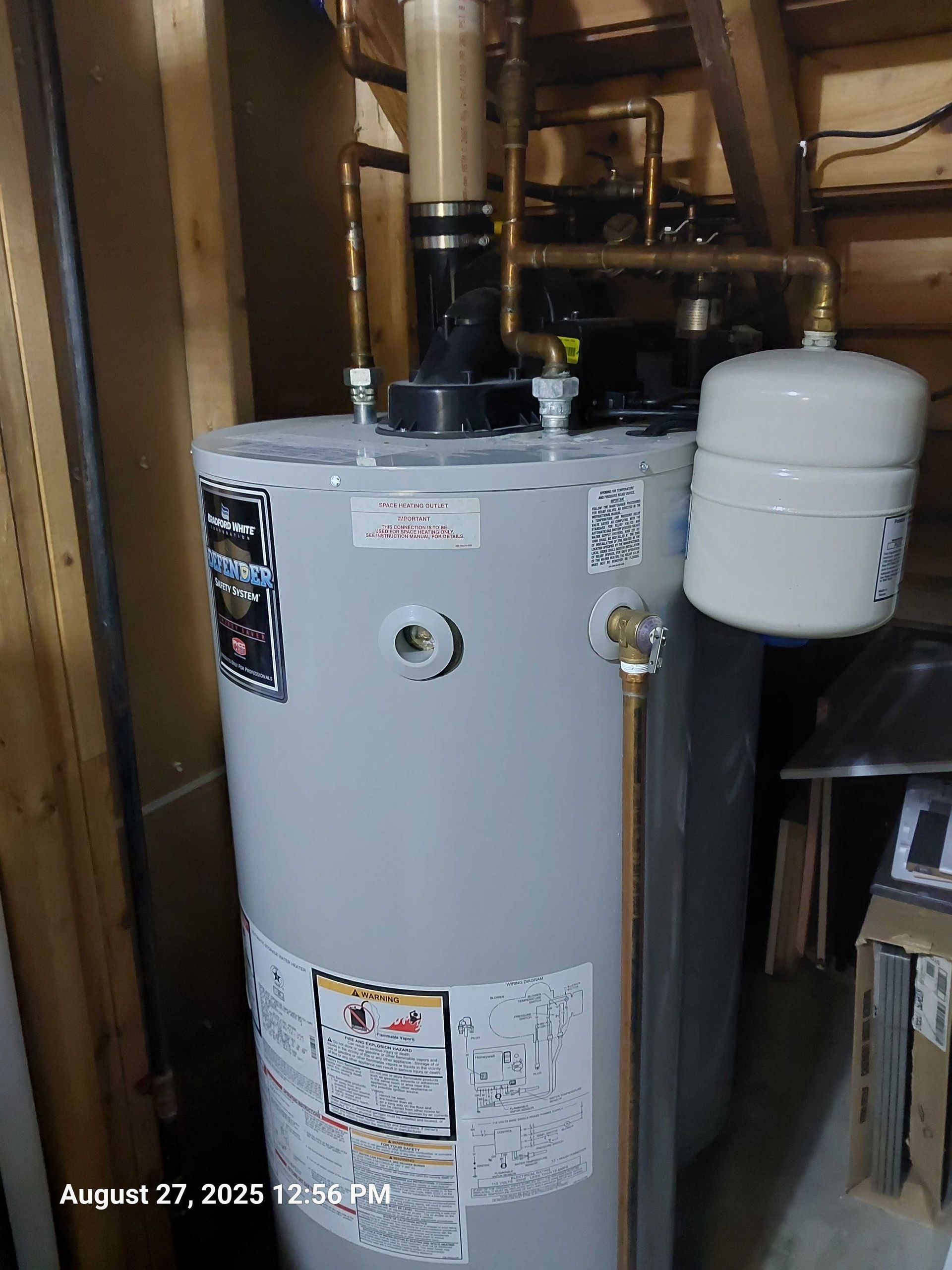 A water heater with copper pipes and expansion tank in a utility room.
