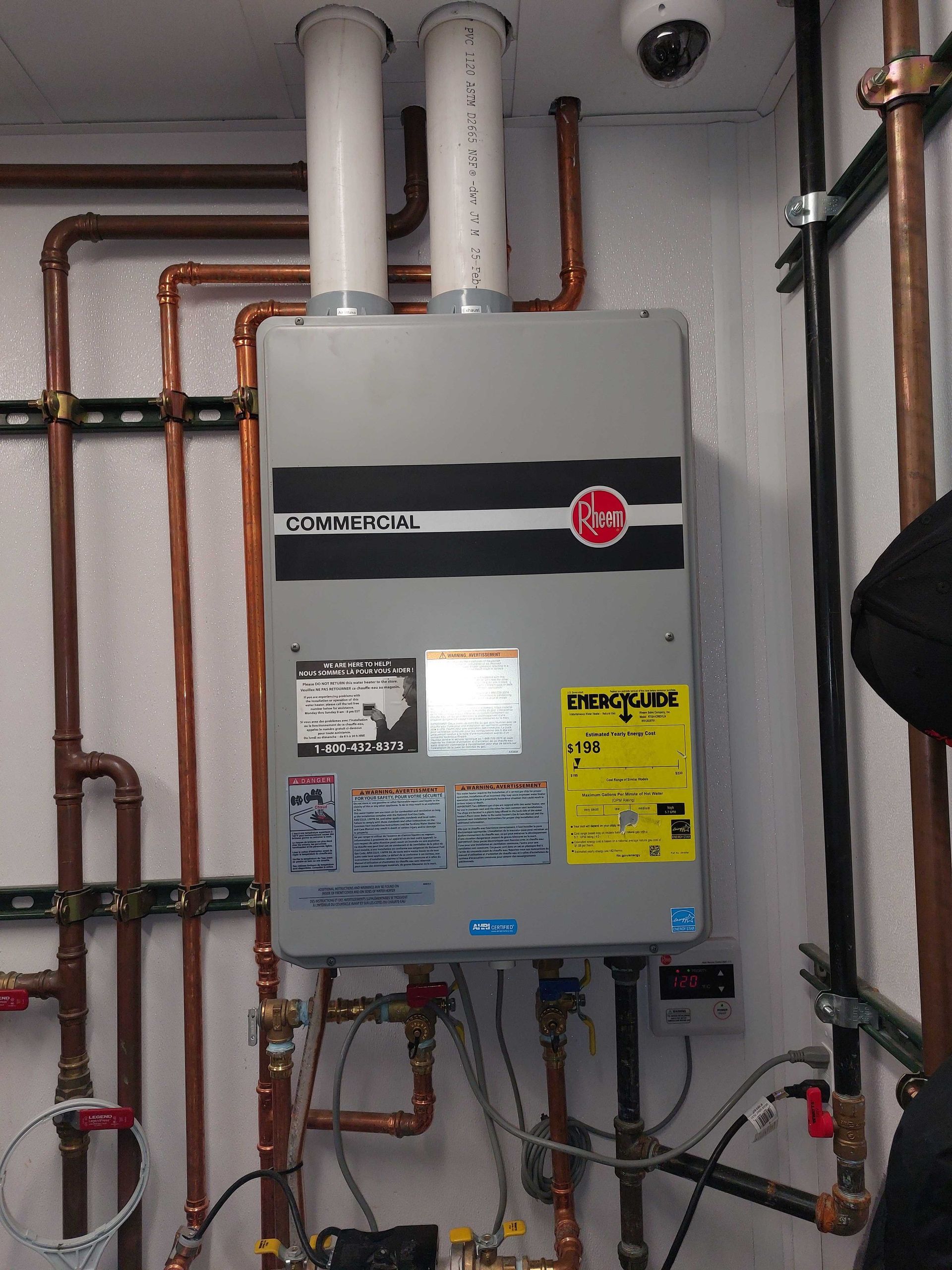 Tankless water heater with copper pipes, venting, and a security camera.