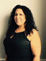 A woman with curly hair is wearing a black tank top and smiling.