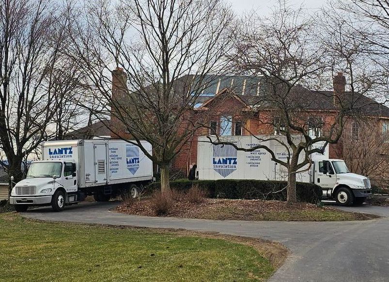 Lantz trucks Two insulation trucks are parked in front of a house.