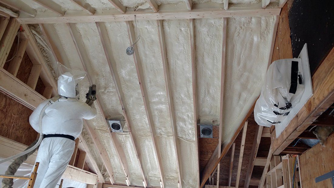 a man is spraying insulation on the ceiling of a building .