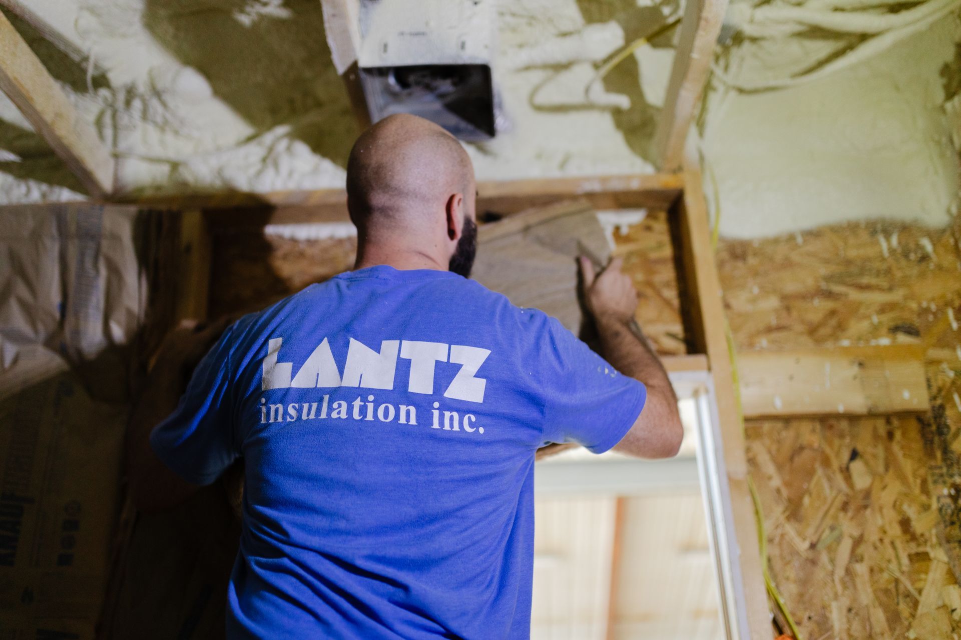 a man in a blue shirt is working in an attic .