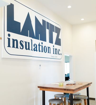 a sign for lantz insulation inc. hangs above a wooden table