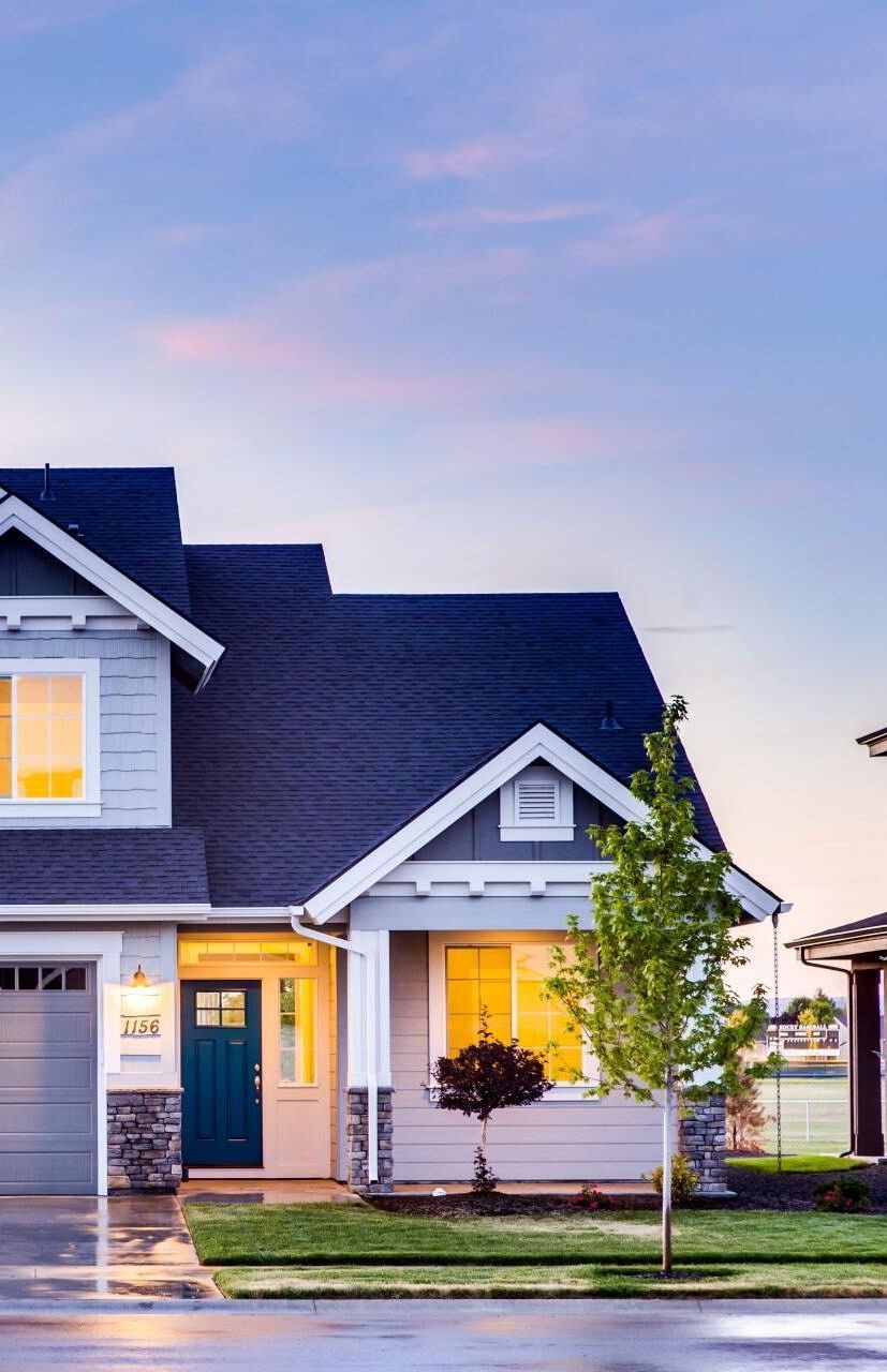 A large house with a blue roof is sitting on a lush green lawn.