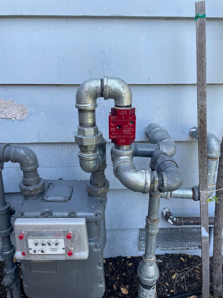 A gas meter with a red valve attached to it.