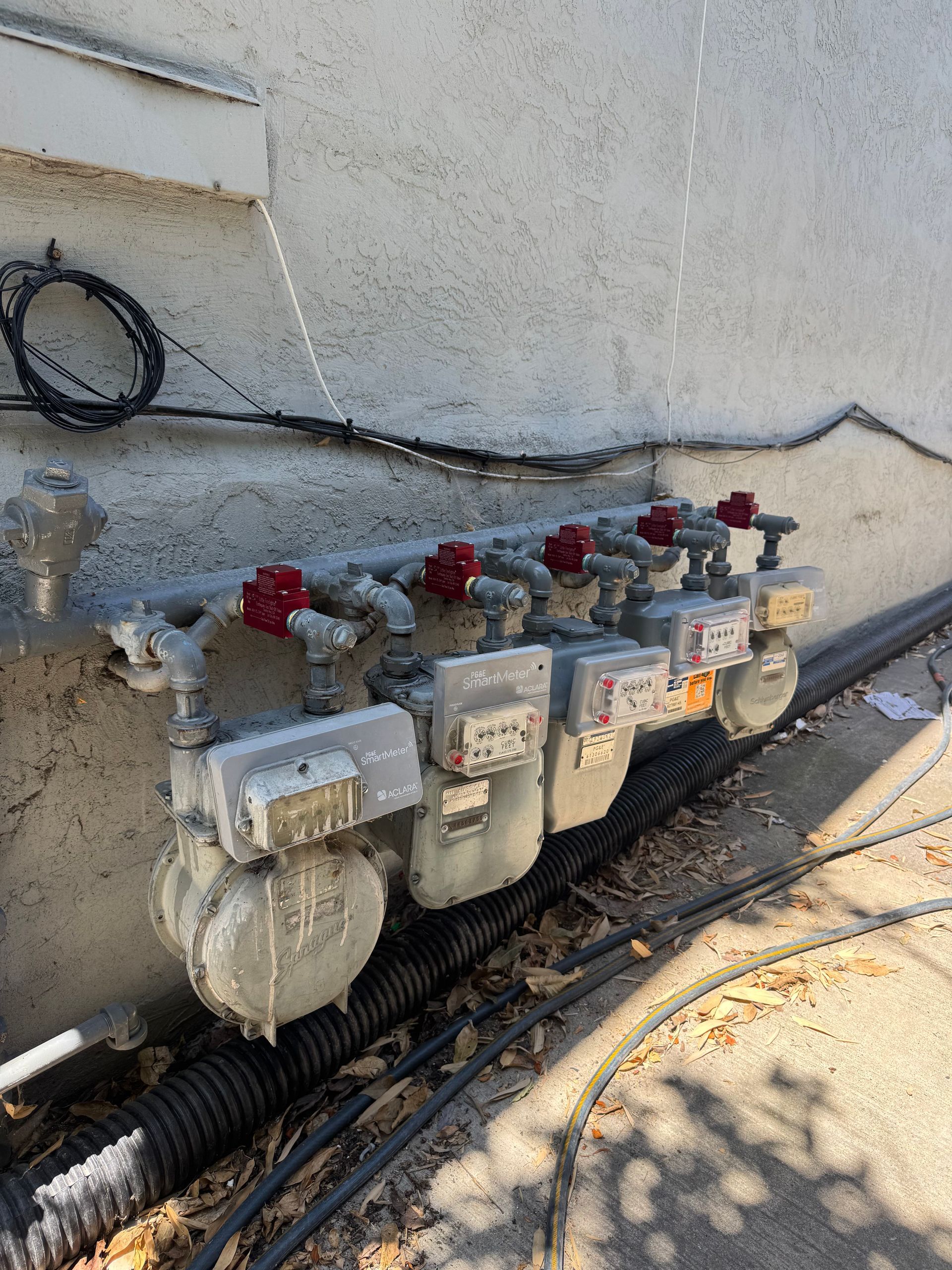 A row of gas meters are sitting on the side of a building.