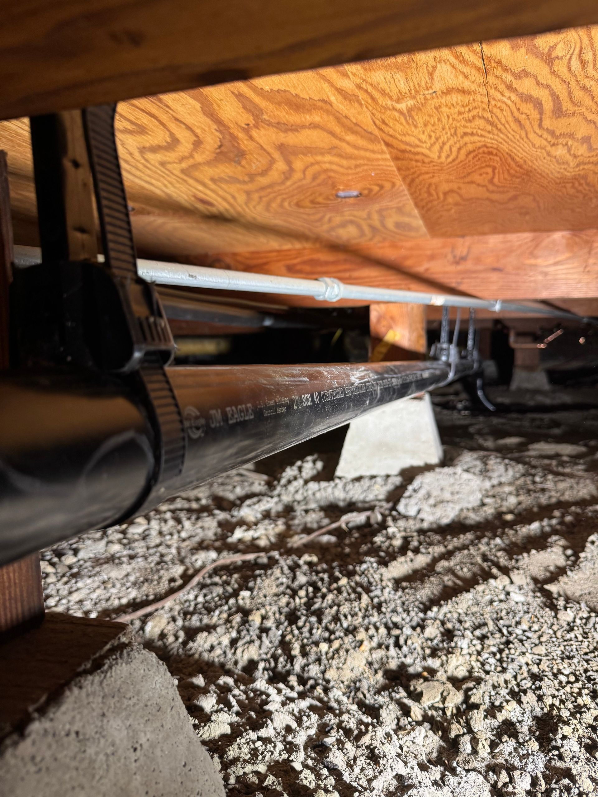 A vacuum cleaner is sitting under a wooden floor in a room.