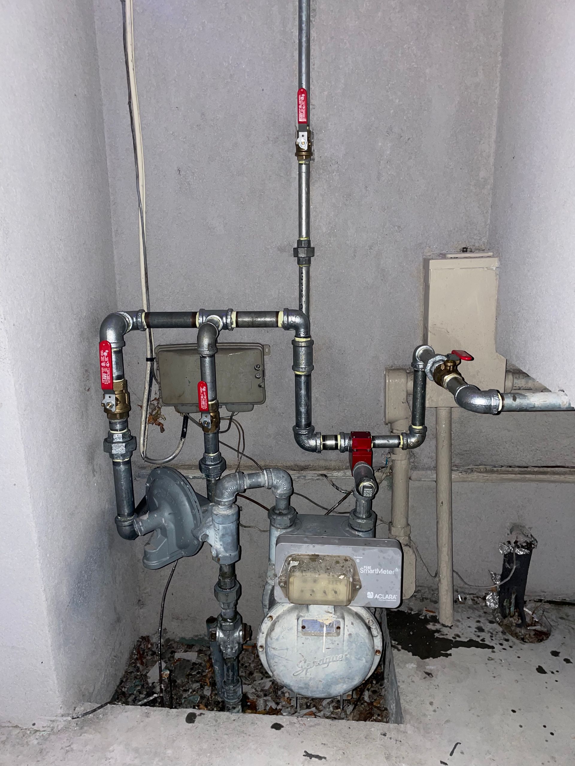 A room with pipes and a gas meter on the floor