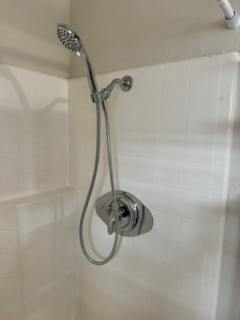 A shower head is hanging from the ceiling in a bathroom.