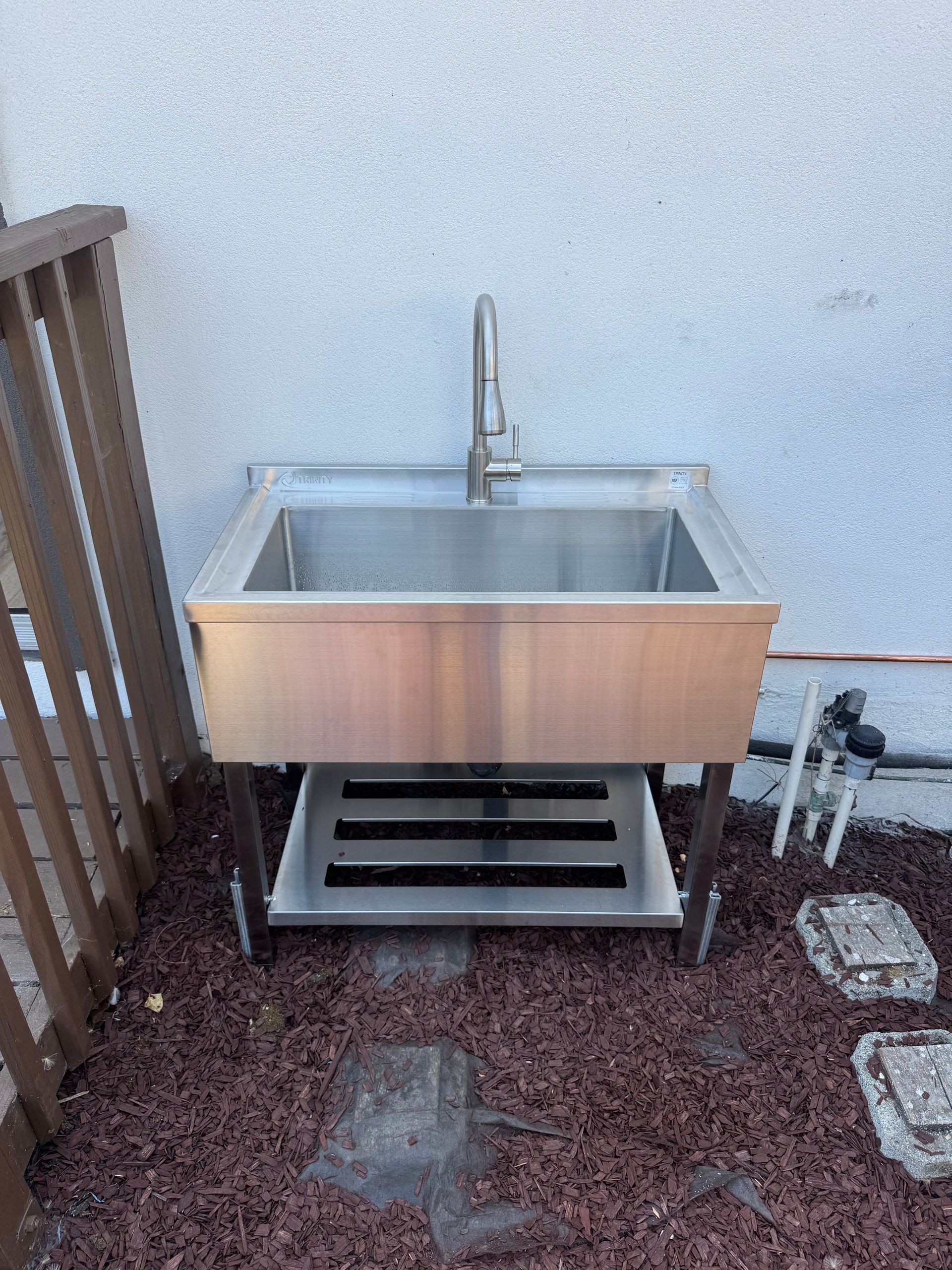 A stainless steel sink is sitting on top of a pile of gravel.