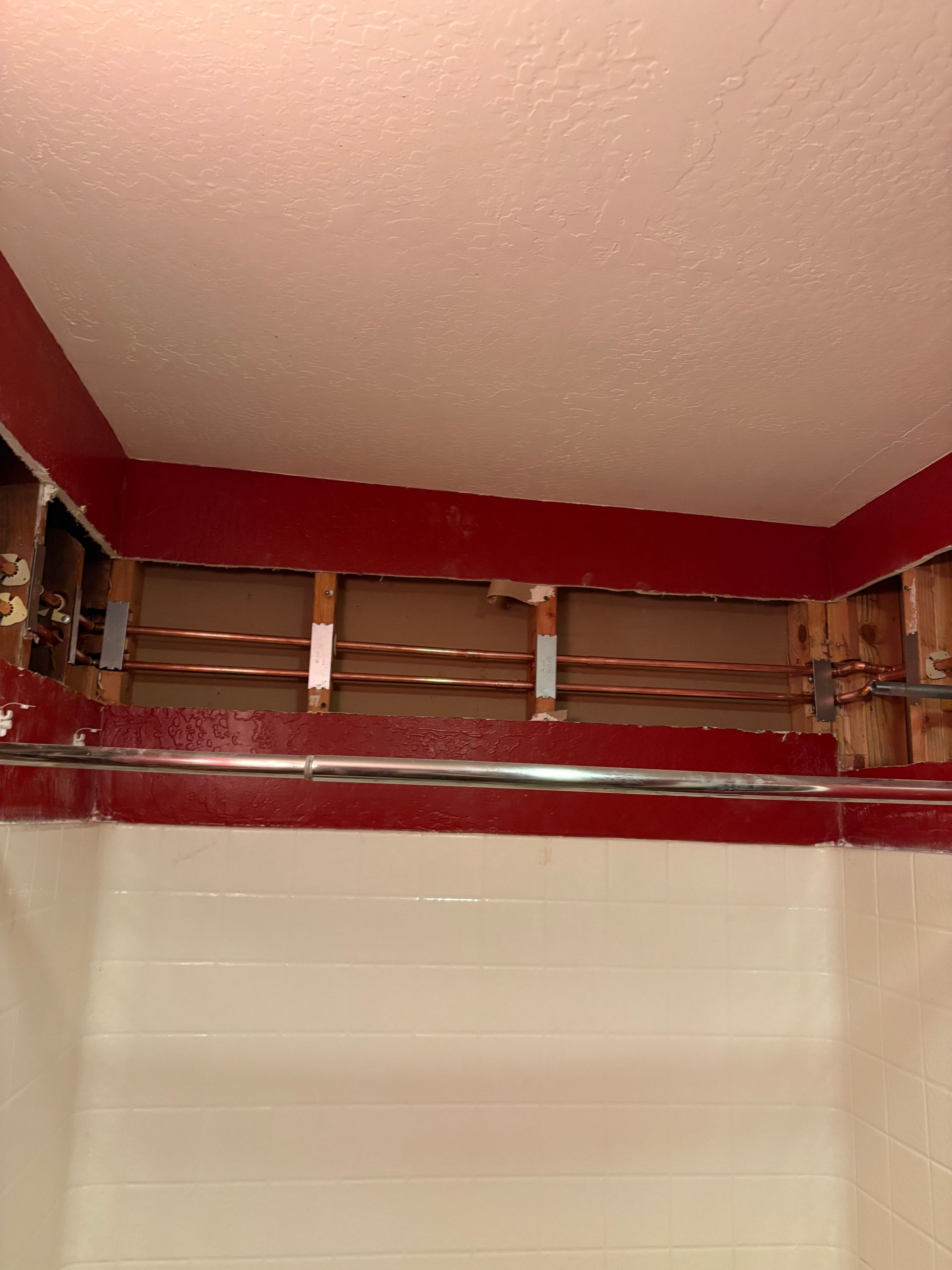A bathroom with a ceiling that is missing and a shower head.